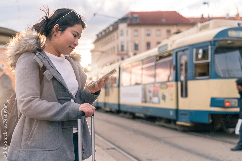 Smiling young asian woman checking schedule table of city traffic online on application using smartp