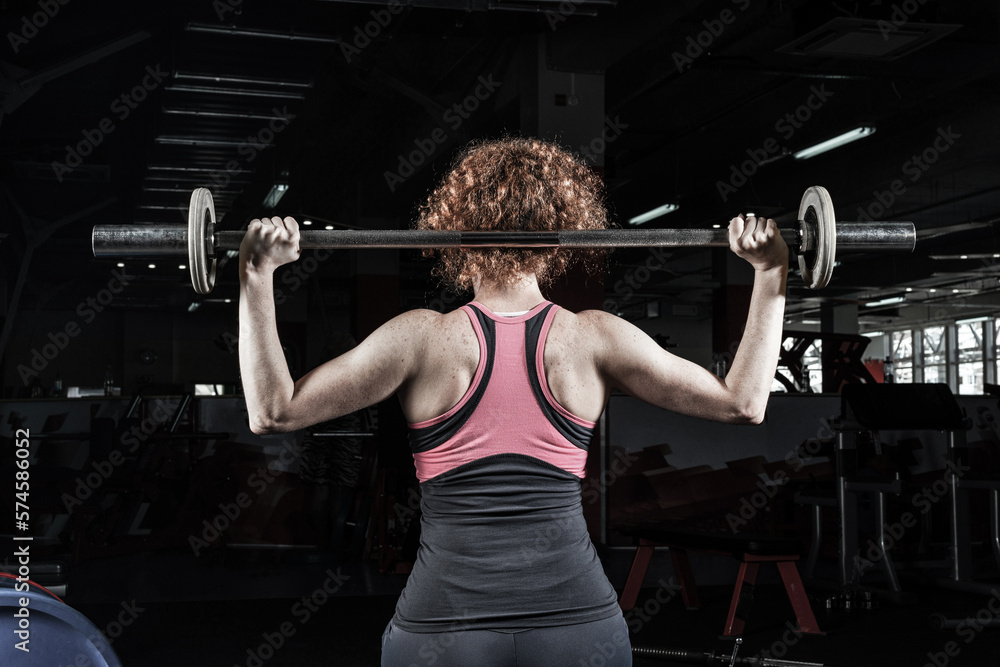 Woman bodybuilder engaged with a barbell in the gym