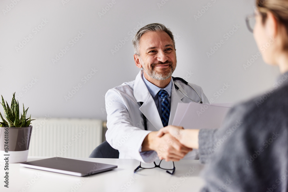 A senior male specialist handshake with a female patient at the office.