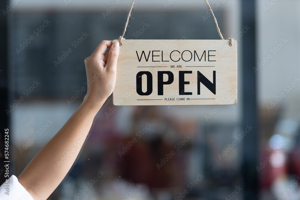 Open sign on the glass door, barista, waitress turning open sign board on glass door in modern cafe 