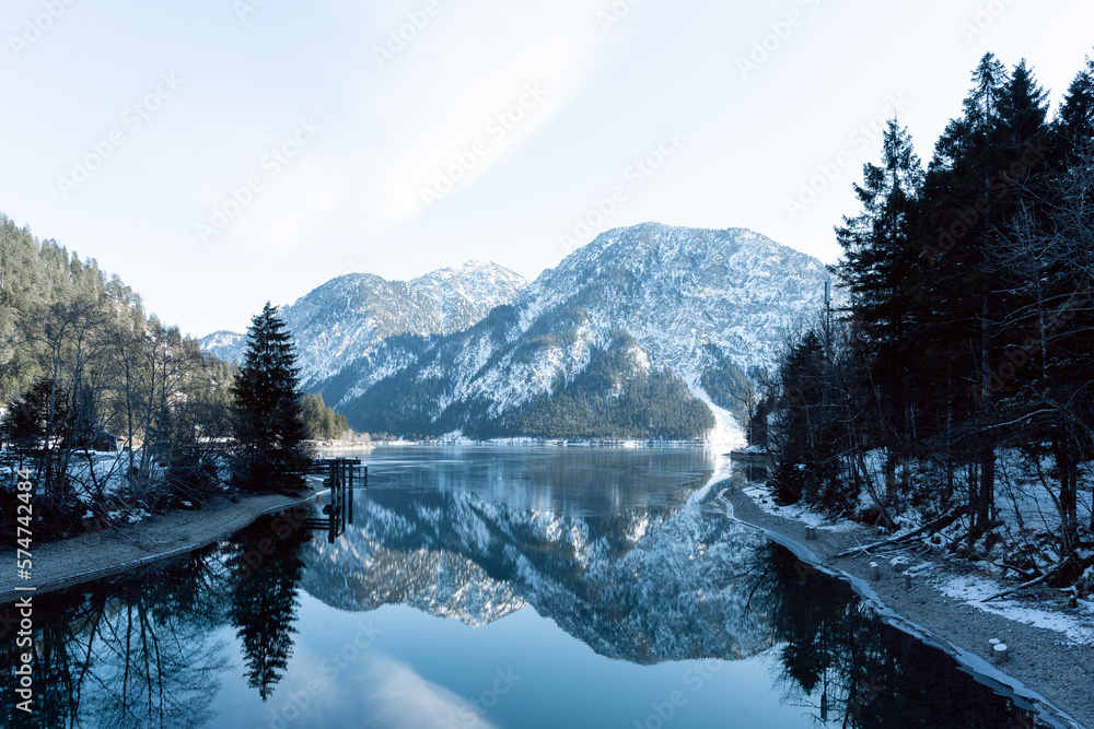 the beautiful lake plansee photographed in the day with the mountains covered with snow and the lake