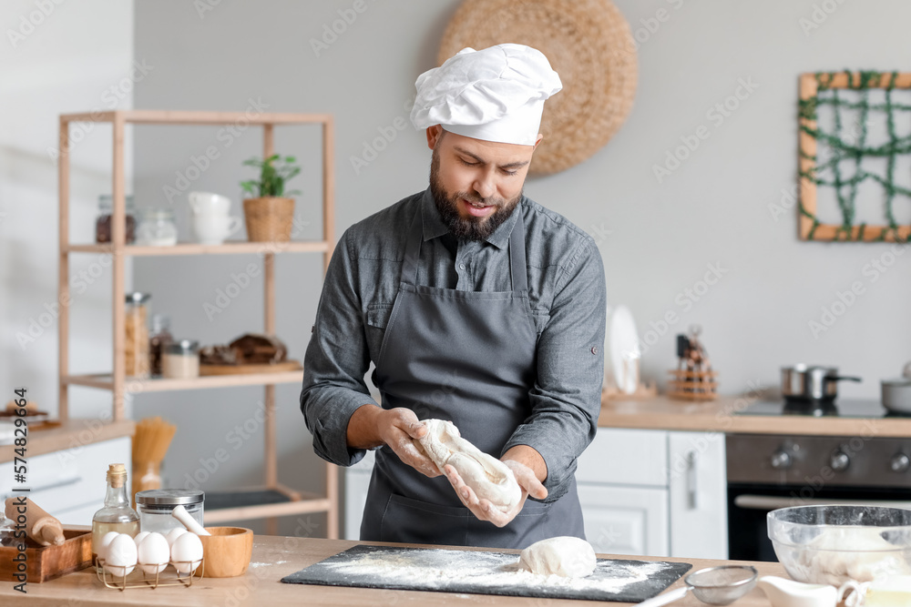 Male baker preparing dough at table in kitchen