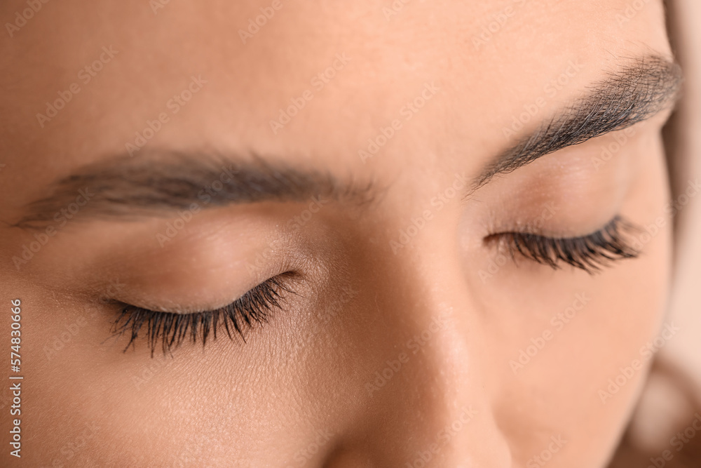 Woman with closed eyes on beige background, closeup