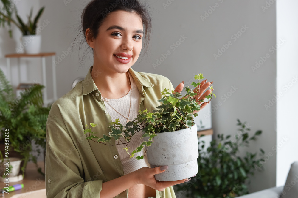 Young woman with green houseplant in kitchen