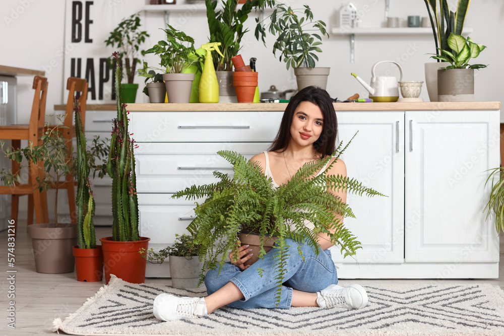 Young woman with green houseplants in kitchen