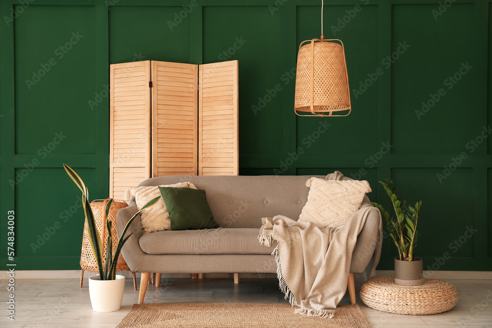 Interior of living room with grey sofa, houseplants and folding screen