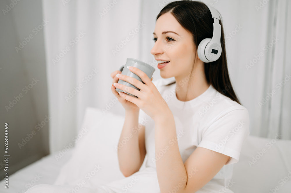 Beautiful young woman on a white bed with coffee cub and using smart phone at home. lifestyle concep