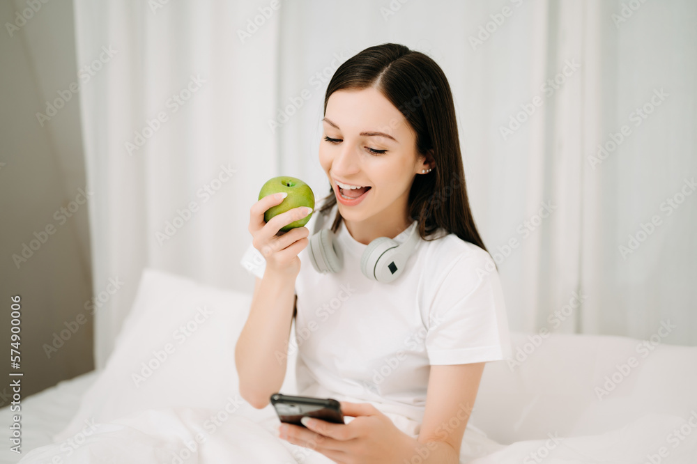 Beautiful woman has woken up on a white bed and holding coffee in the morning at home in morning