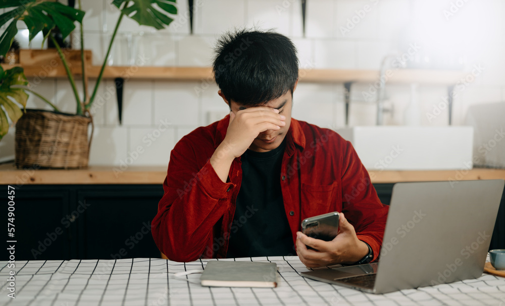 Asian business man is stressed, bored, and overthinking from working on a tablet at the modern offic