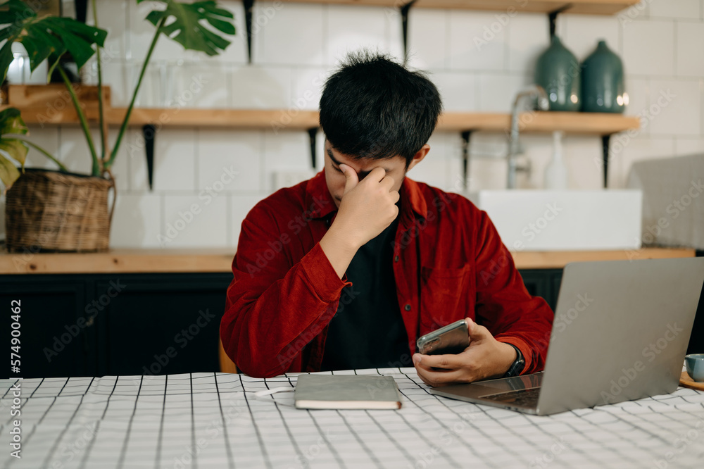 Asian business man is stressed, bored, and overthinking from working on a tablet at the modern offic