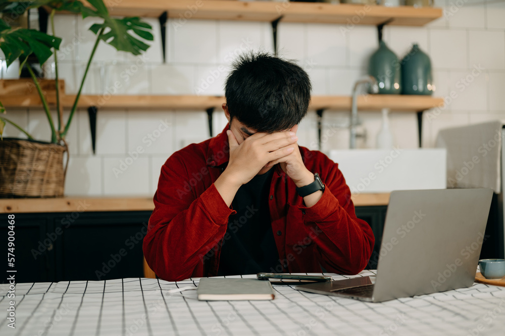 Asian business man is stressed, bored, and overthinking from working on a tablet at the modern offic