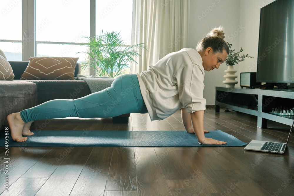 Woman doing online yoga at home. Female teaches asana in video conference. Health care, authenticity