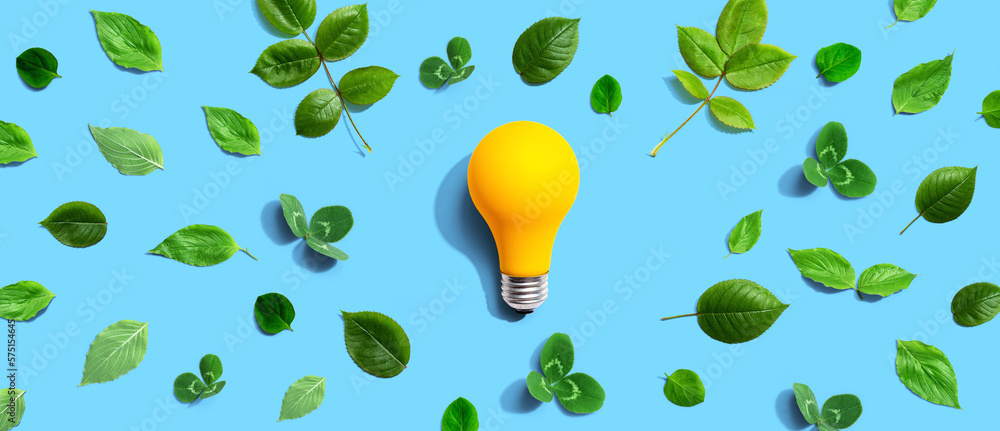 Yellow light bulb with green leaves - Flat lay