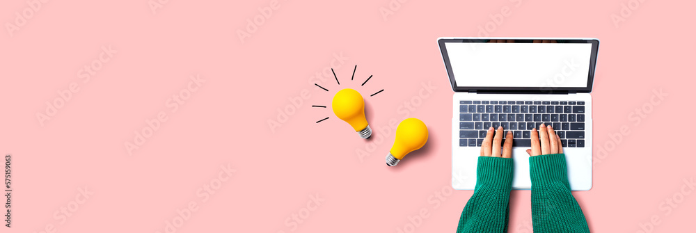 Person using a laptop computer and light bulbs - Flat lay