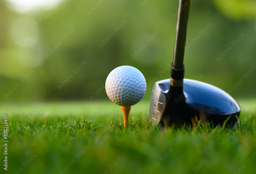 Close-up golf ball on tee with golf drivers at golf course.