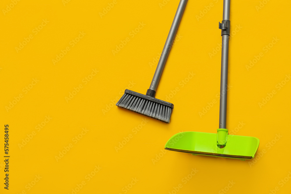 Cleaning broom with dustpan on yellow background