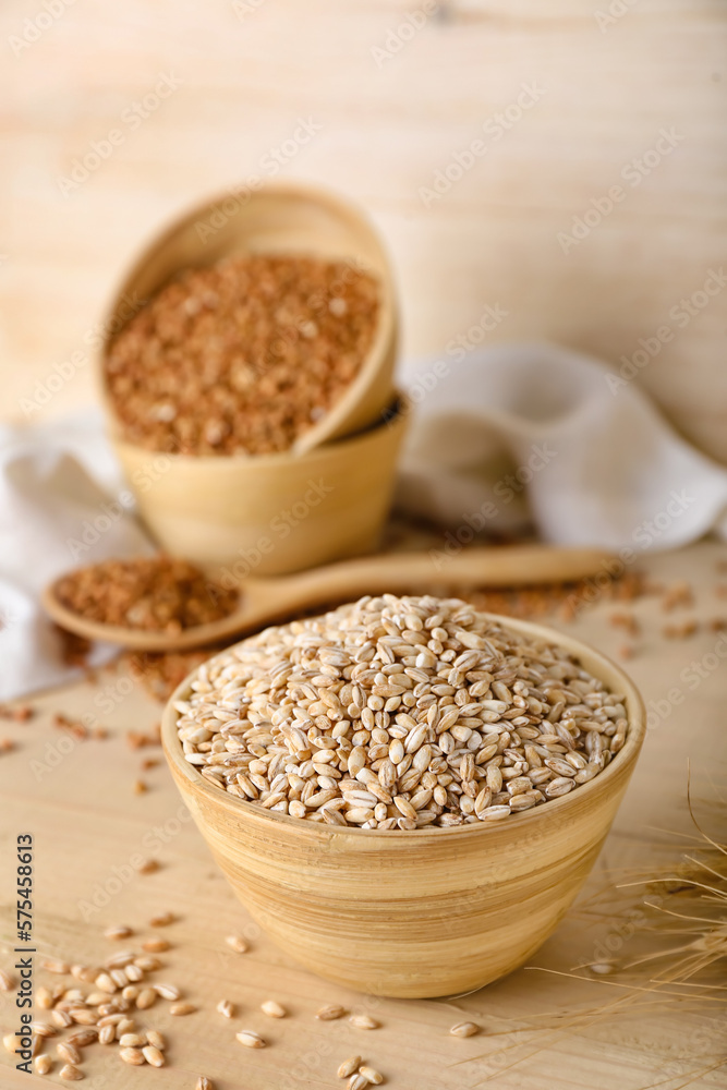 Bowl with pearl barley on wooden background