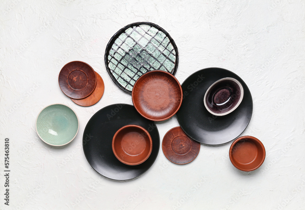 Composition with clean ceramic plates and bowls on white background