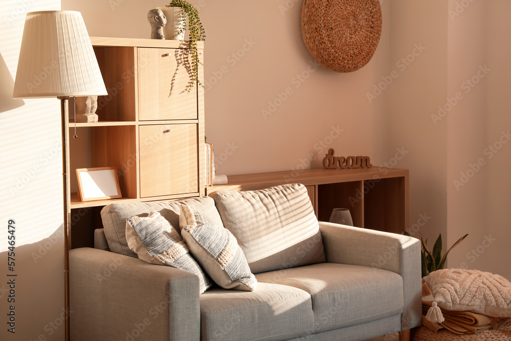 Interior of modern living room with cozy cushions on grey sofa