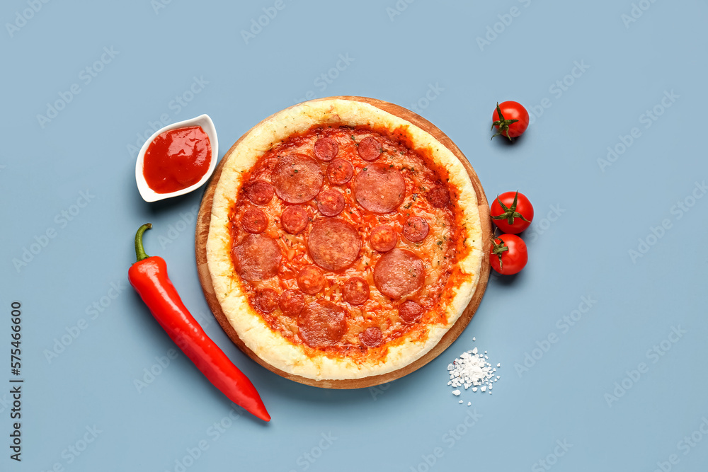 Delicious pepperoni pizza, tomatoes, jalapeno pepper and sauce on blue background