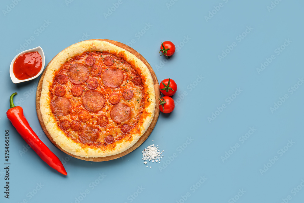 Delicious pepperoni pizza, tomatoes, jalapeno pepper and sauce on blue background