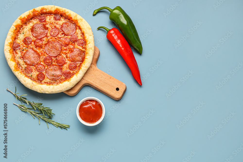 Board with delicious pepperoni pizza and jalapeno peppers on blue background