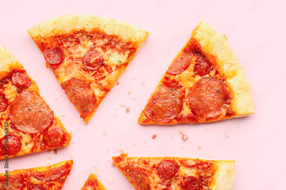 Slices of delicious pepperoni pizza on pink background