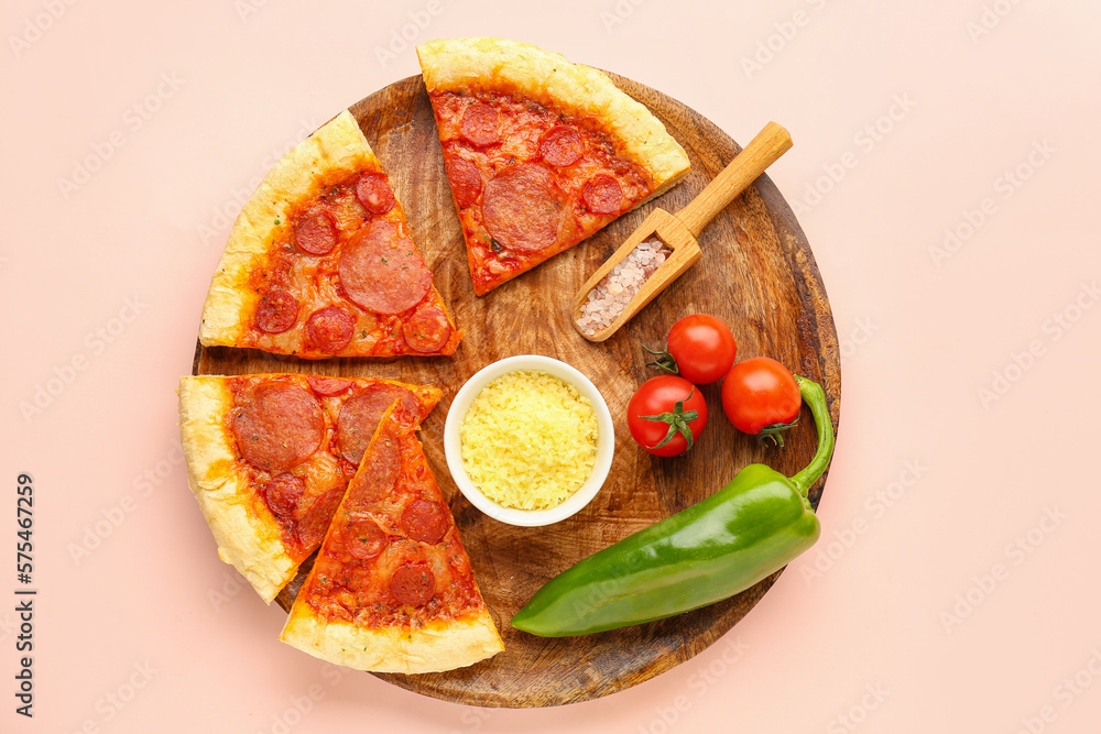 Board with slices of delicious pepperoni pizza, jalapeno pepper, tomatoes and salt on pink backgroun