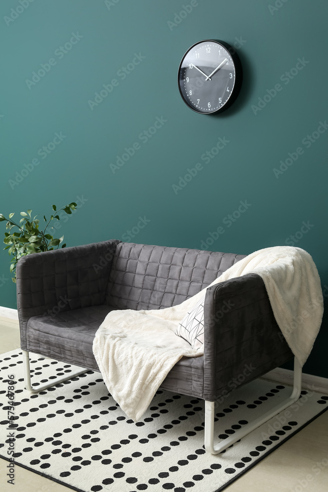 Stylish grey sofa and houseplant near green wall