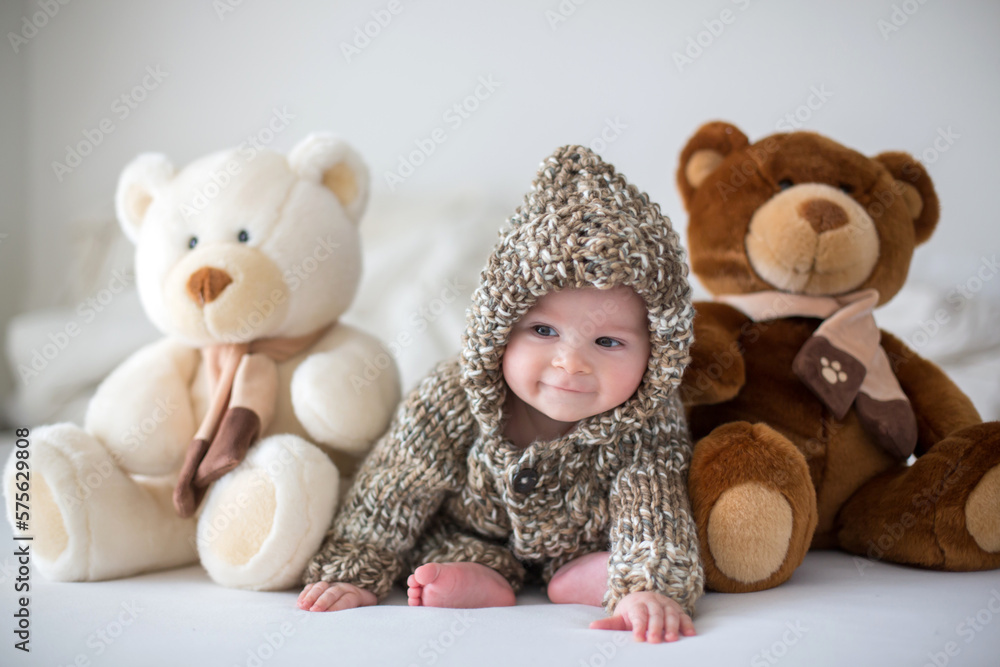 Little baby boy playing at home with soft teddy bear toys, lying down