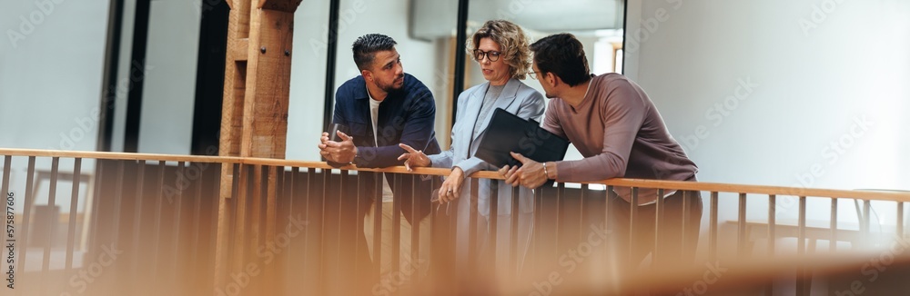 Discussion in an office. Three business people talking on an interior balcony