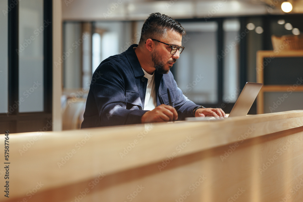 Graphic designer working on a laptop in a coworking office