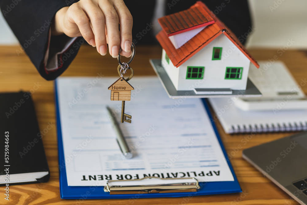 Real estate agent holding keys and model house showing to client, rental house concept.