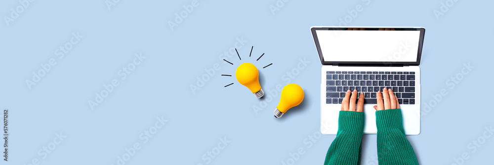 Person using a laptop computer and light bulbs - Flat lay