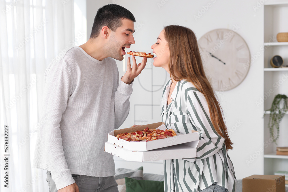 Happy young couple eating tasty pizza at home