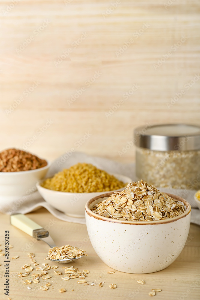 Bowl of raw oatmeal flakes on wooden table