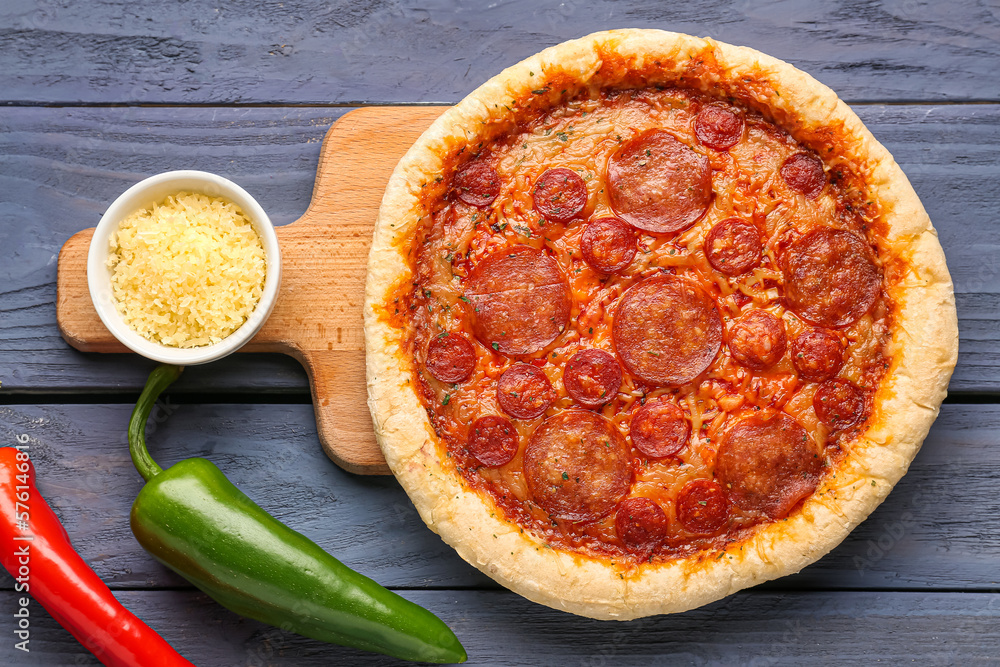 Board with delicious pepperoni pizza and jalapeno peppers on blue wooden background