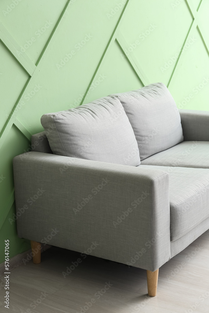 Stylish grey sofa near green wall