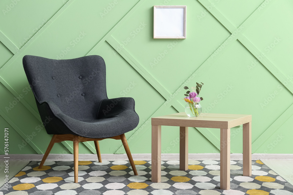 Modern grey armchair and table near green wall