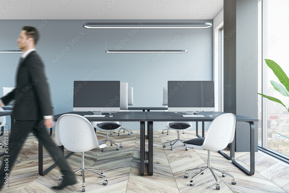 Businessman walking in modern coworking office room interior with furniture, equipment and window wi