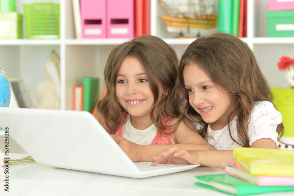 Two cute little girls at class with laptop