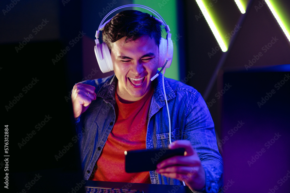 Young man cheering as he plays games on his mobile phone