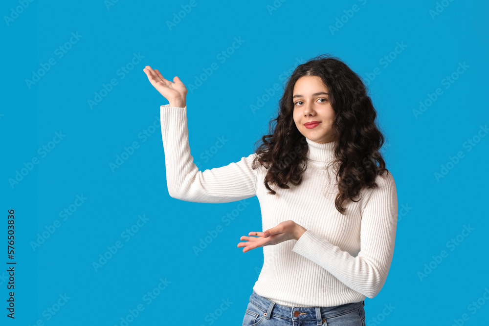 Teenage girl showing something on blue background