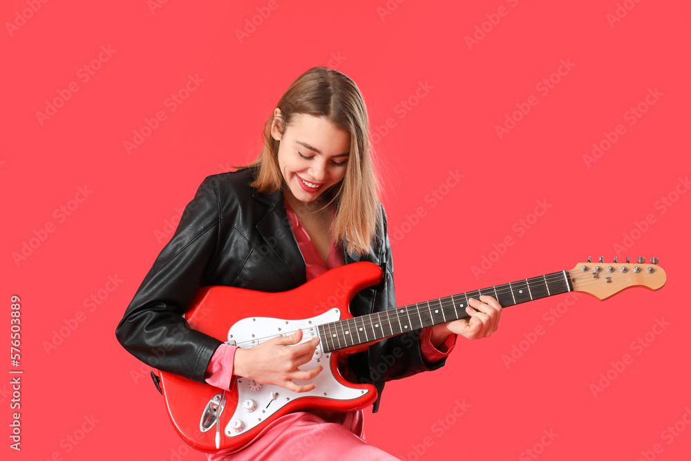 Young woman playing guitar on red background