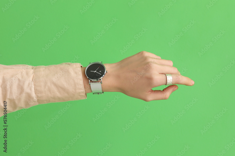 Woman with stylish wristwatch on green background