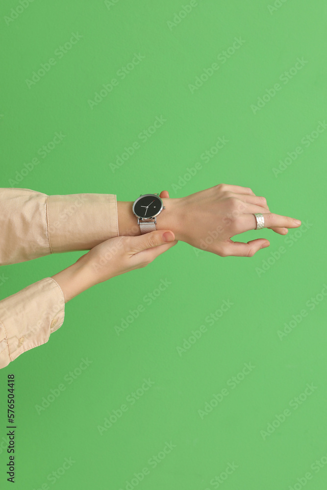 Woman with stylish wristwatch on green background