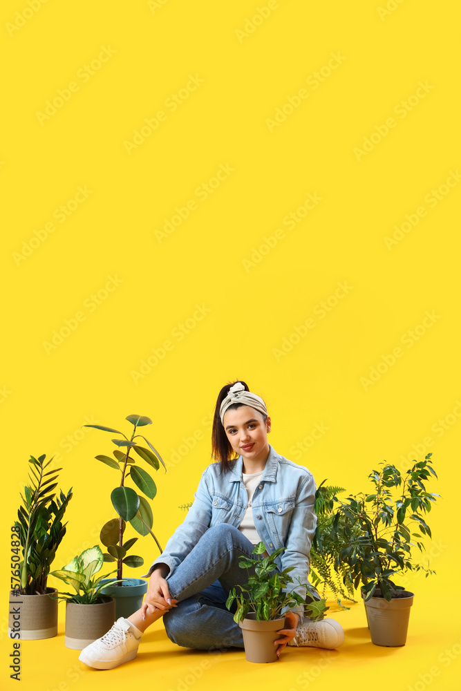 Young woman with green houseplants sitting on yellow background