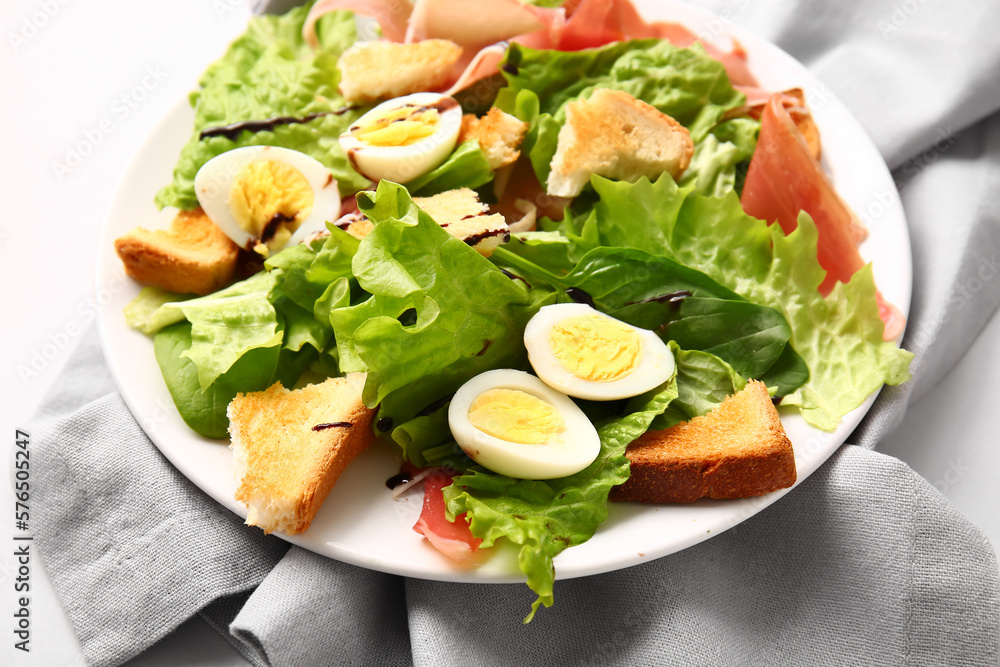 Plate of delicious salad with boiled  eggs and jamon on grey background