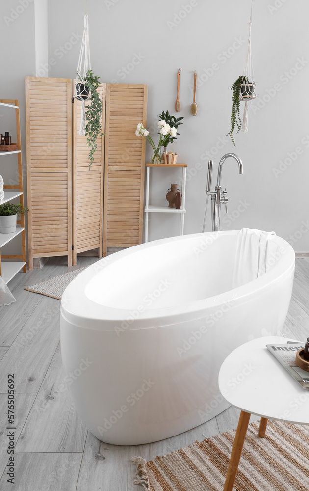 Interior of bathroom with ranunculus flowers in vase and bathtub