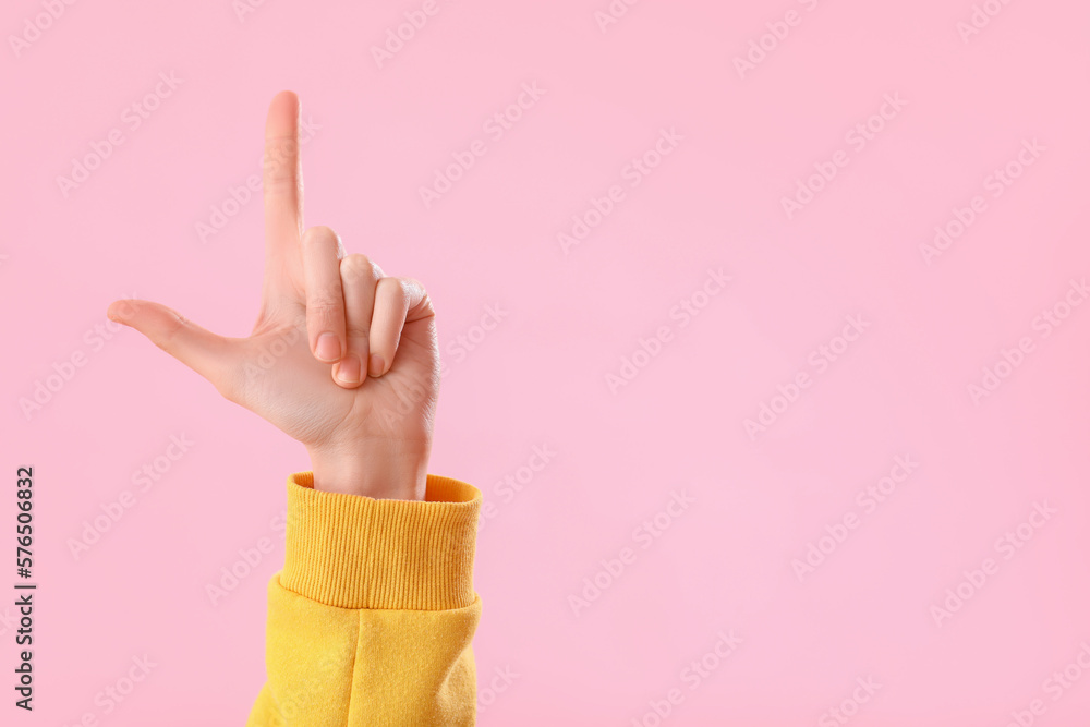 Young woman showing loser gesture on pink background